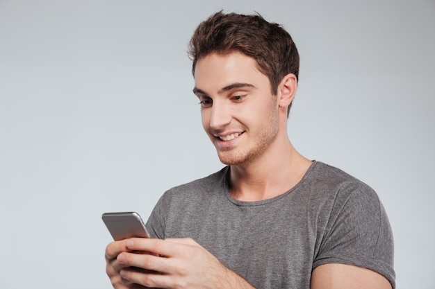 Nahaufnahmeporträt eines attraktiven zufälligen Mannes, der das Handy lokalisiert auf Weiß verwendet