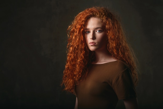 Nahaufnahmeporträt eines jungen Mädchens mit rotem lockigem Haar in einem khakifarbenen Kleid