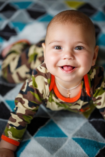 Nahaufnahmeporträt eines kleinen Jungen im Alter von 8 Monaten und lächelt. In Militärkostüm gekleidet