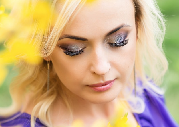 Nahaufnahmeporträt eines Mädchens mit professionellem Make-up. schöne Frau in einem lila Kleid mit blühender Forsythie.