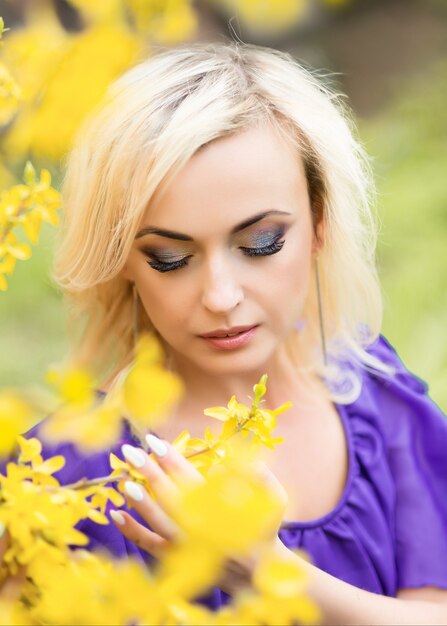 Nahaufnahmeporträt eines Mädchens mit professionellem Make-up. schöne Frau in einem lila Kleid mit blühender Forsythie.