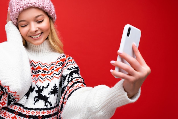 Nahaufnahmeporträt Foto der ziemlich schüchternen positiven jungen blonden Frau, die warmen Strickmütze und Winter trägt