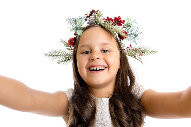 Nahaufnahmeporträt selfie eines fröhlichen mädchens in einem weihnachtskranz, der die kamera umarmt