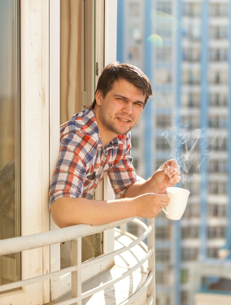 Nahaufnahmeporträt von Hipster-Kerl, der Kaffee auf dem Balkon trinkt