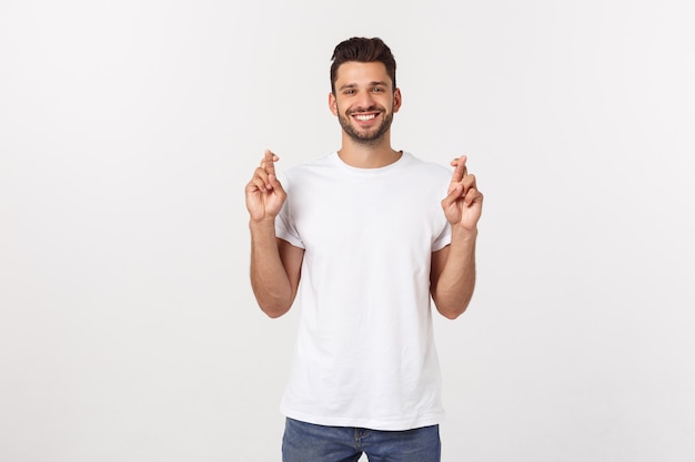 Nahaufnahmeporträt von Überfahrtfingern des jungen gutaussehenden Mannes, Wunsch, betend für Wunder und hoffen auf das Beste, lokalisiert auf Weiß.