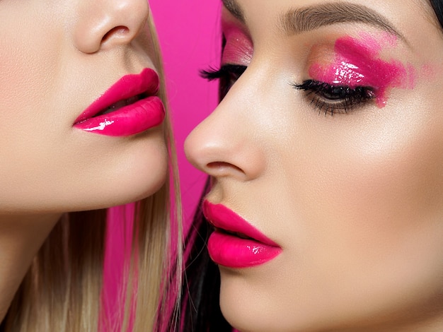 Nahaufnahmeporträt von zwei jungen schönen Frauen mit Mode rosa Make-up. Hellrosa Lipgloss und Lidschatten. Hautpflege-, Kosmetik-, SPA-Therapie- oder Kosmetikkonzept