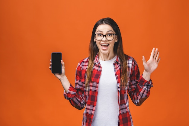 Nahaufnahmeporträtkopfschussfrau unter Verwendung des Mobiltelefons lokalisiert über orange Wandhintergrund