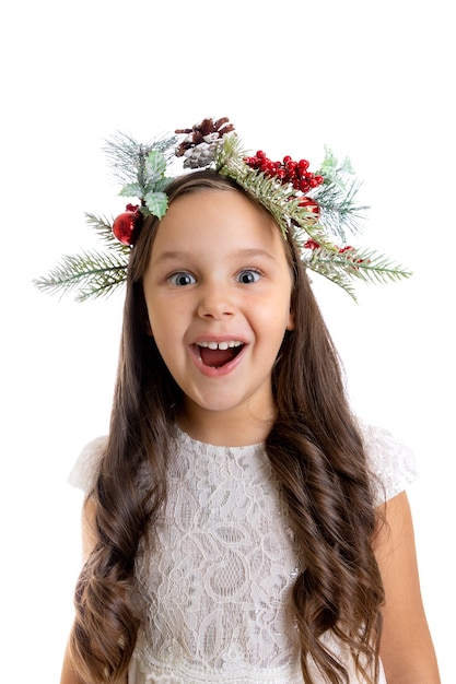 Nahaufnahmeportrait des überraschten Mädchens mit offenem Mund im Weihnachtskranz und in den Locken lokalisiert auf wei...