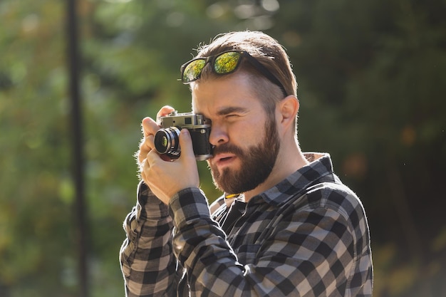 Nahaufnahmeportrait-Mannfotograf, der Foto mit Weinlesekamera auf Stadtgrünpark-Freizeitbeschäftigung und Hobbykonzept macht