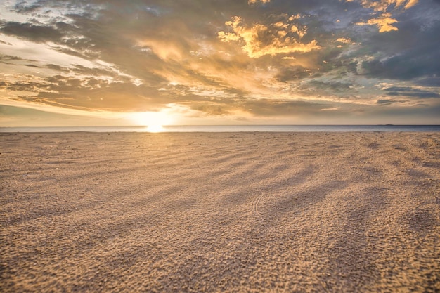 Nahaufnahmesandbeschaffenheit mit Lichtstrahlen des Sonnenuntergangs. Goldene orange Sonnenunterganghimmelwolken. Insel im Mittelmeer