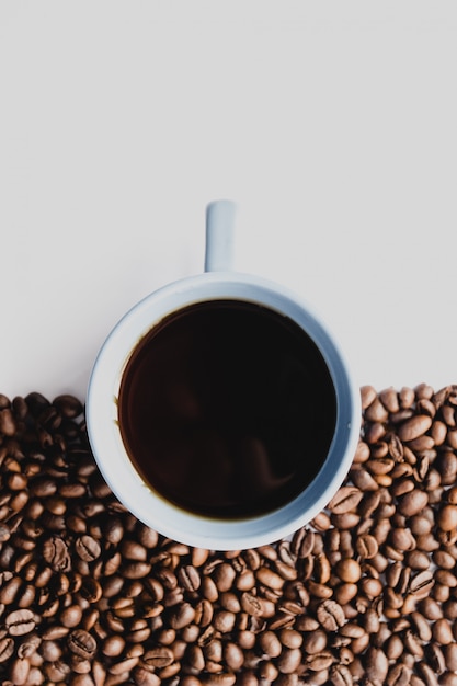 Nahaufnahmeschuss einer Tasse Kaffee mit Kaffeebohnen auf Weiß