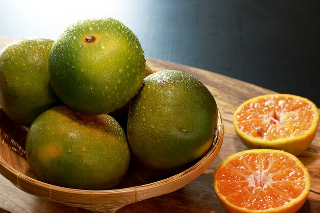 Nahaufnahmetangerinen oder Klementinen oder Orangen, im hölzernen Korb auf Holztisch. Früchte-Konzept.