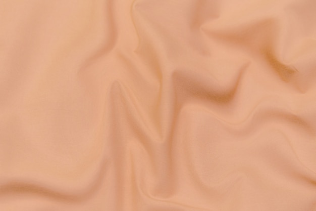 Nahaufnahmetextur aus orangefarbenem oder braunem Stoff oder Stoff in derselben Farbe. Gewebestruktur aus natürlicher Baumwolle, Seide oder Wolle oder Leinentextilmaterial. Stoff Leinwand Hintergrund.