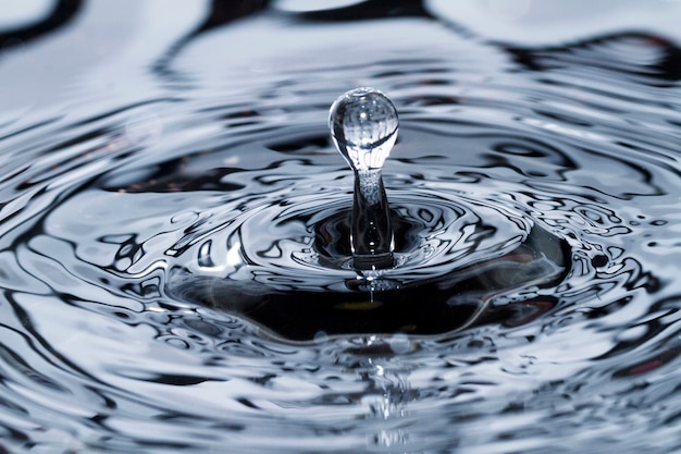 Nahe Ansicht eines Wassertropfens, der eine Oberfläche des Wassers schlägt.