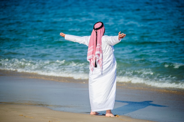 Naher Osten gekleideter arabischer Mann wirft vor Seeküste auf.