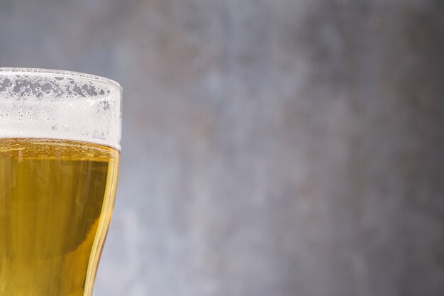 Nahes helles Bier im Glas auf grauer Wand