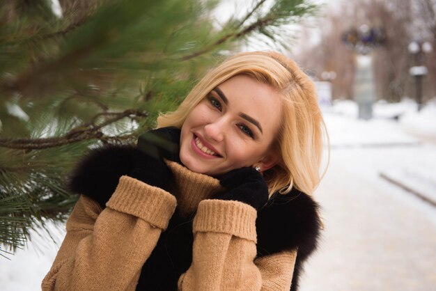 Nahes hohes Foto im Freien der jungen schönen glücklichen lächelnden Frau, die auf Straße im Winter geht.