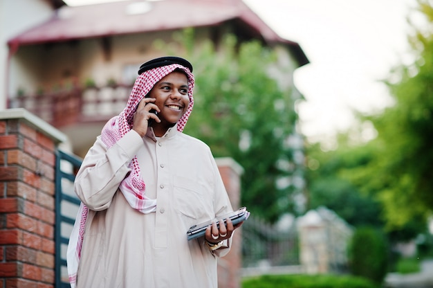 Nahöstlicher arabischer Geschäftsmann warf auf Straße gegen modernes Gebäude mit Tablette und Handy an den Händen auf.