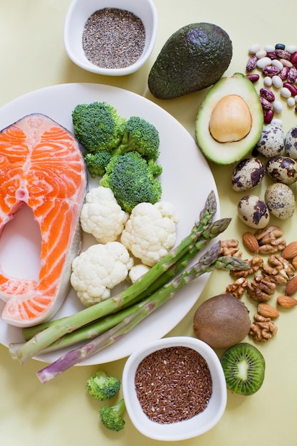 Nahrungsquellen von Omega 3 auf gelbem Hintergrund Frisches Gemüse, Fischsamen und Nüsse, gesundes Ernährungskonzept
