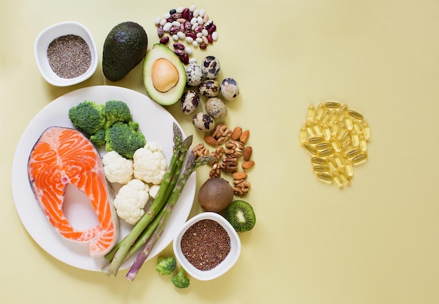 Foto nahrungsquellen von omega 3 auf gelbem hintergrund omega-3-pillen und frisches gemüse, fischsamen und nüsse gesundes ernährungskonzept