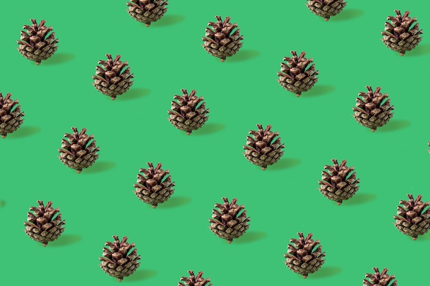 Nahtloses Weihnachtsmuster von Tannenzapfen auf grünem Hintergrund
