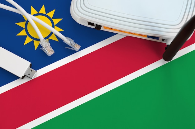 Namibia Flagge auf dem Tisch mit Internetkabel, WLAN-WLAN-Adapter und Router abgebildet. Internetverbindungskonzept