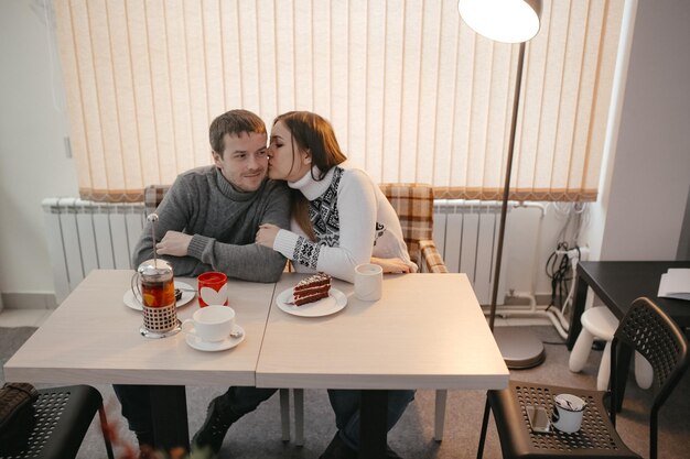 Foto namorada a beijar o namorado num café.