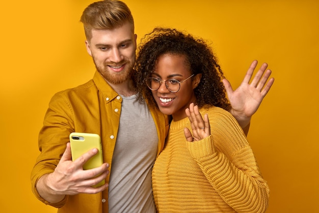 Namorada africana e namorado caucasiano tirar selfie no telefone e fazer videochamada para a câmera