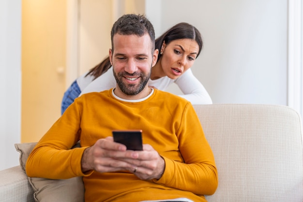 Namorada ciumenta tenta espiar o smartphone do namorado, fica triste enquanto ele manda mensagem para alguém