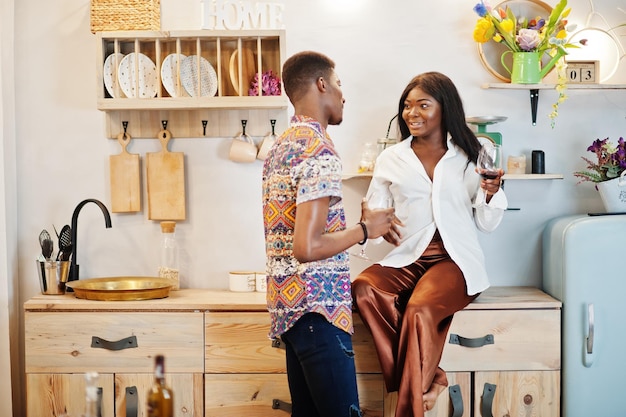 Namoradas de casal afro-americano bebendo vinho na cozinha em seu encontro romântico