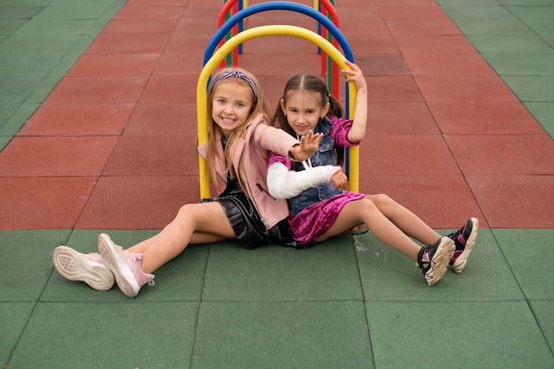 Namoradas estão sentadas na cobertura de borracha do playground