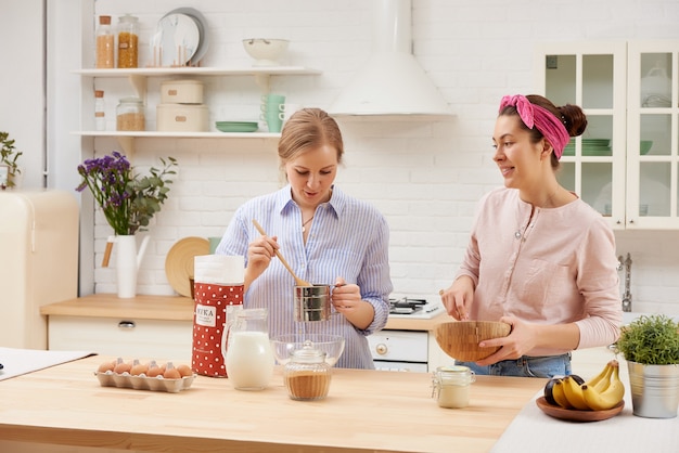 namoradas felizes preparam café da manhã na cozinha