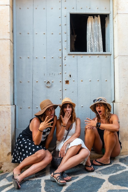 Namoradas no verão, aproveitando as férias. Três amigos sentados em uma porta de madeira no Mediterrâneo. Espanha