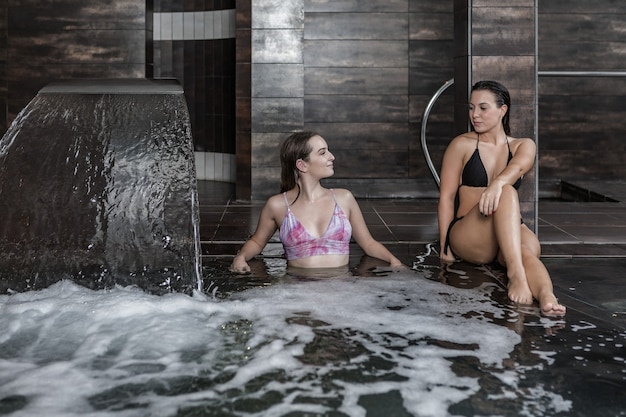 Namoradas relaxando durante procedimento de hidroterapia na piscina do spa