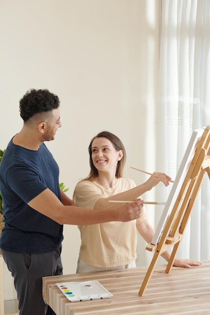 Namorado e namorada sorrindo pintando na tela quando ficam em casa devido ao bloqueio