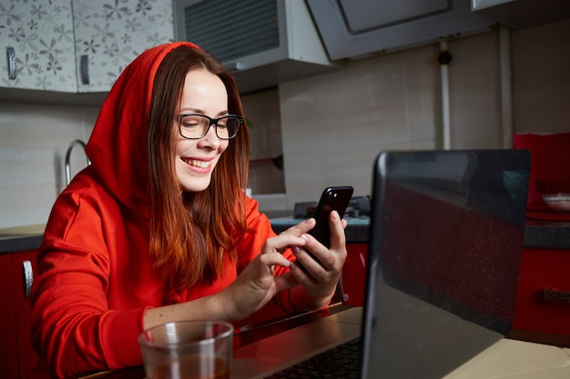 Namoro virtual. Retrato de uma mulher ruiva satisfeita, sentada na cozinha e fazendo videochamada no laptop