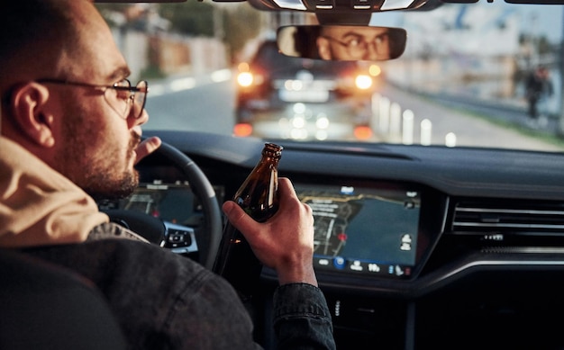 Não beba e dirija vista traseira de um homem bonito e sem barba em roupas da moda dentro de seu automóvel