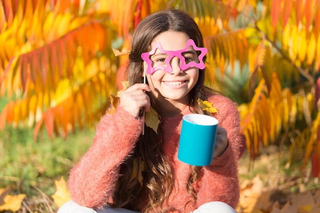 Não é engraçado, eu amo o cheiro das folhas de outono pela manhã Criança feliz segurando a xícara de café na manhã de outono Garota pequena bebe café ou chá da manhã Bom dia divertido