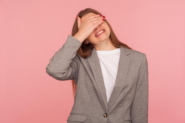 Não quero olhar retrato de jovem descontente em terno de negócios cobrindo os olhos com a mão seu rosto expressando desgosto vergonha bruta com medo de assistir tiro de estúdio isolado no fundo rosa