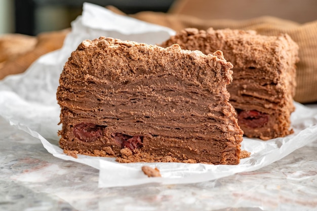 Napoleon-Kuchen mit Pudding ist mit Kirschen und geriebener Schokolade auf dem Tisch dekoriert