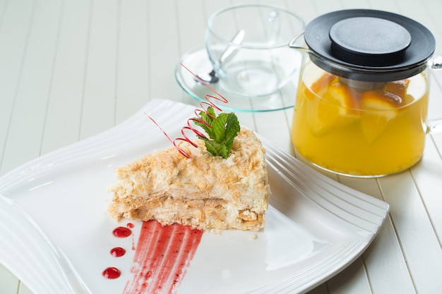 Napoleon-Kuchen verziert mit einer Spirale aus roter Schokolade, Minze und Beerenmarmelade auf einem weißen Teller