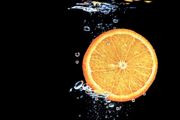 Naranja en agua sobre un fondo negro bajo el agua con burbujas