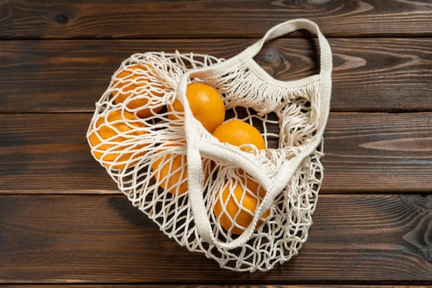 Naranja en bolsa ecológica sobre mesa de madera