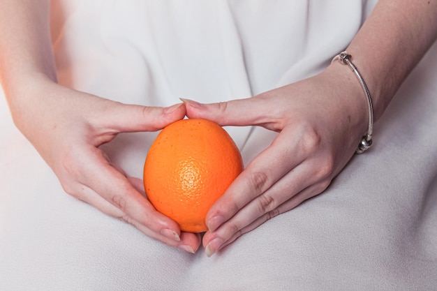 Naranja brillante madura en tiernas manos femeninas