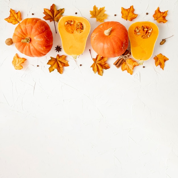 Naranja calabazas en hojas con fondo blanco.