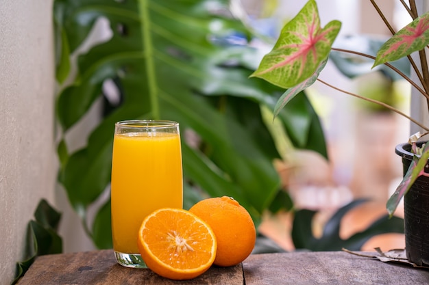 Naranja cortada a la mitad contra el vaso de jugo de naranja sobre la mesa de madera