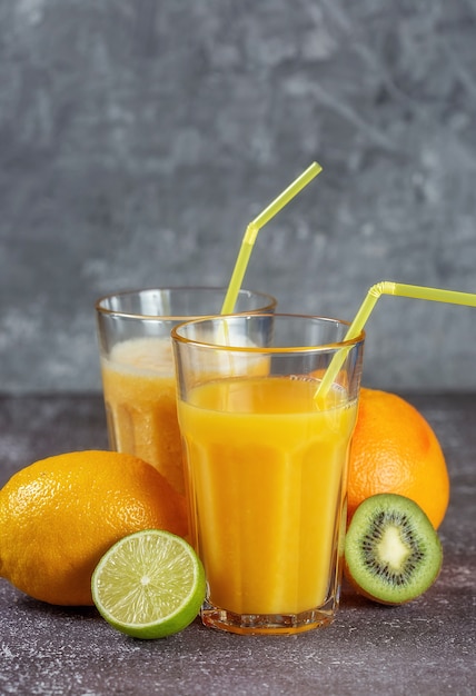 Una naranja envuelta con una cinta métrica y un calibre rodeada de frutas frescas y vasos de jugo y batidos. El concepto de adelgazamiento, da forma a la figura.