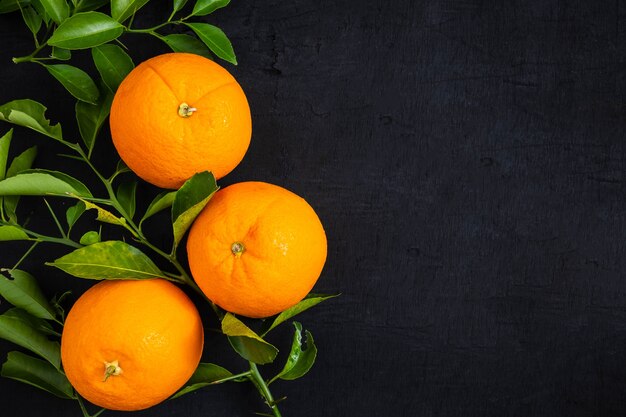 Naranja fresca y hojas sobre fondo negro