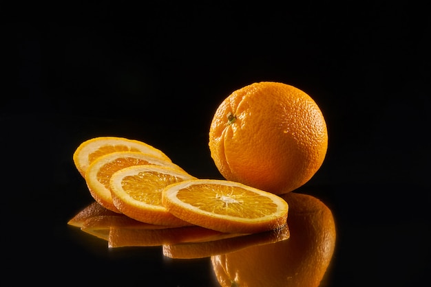 Naranja fresca en rodajas sobre fondo negro