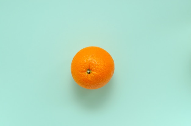 Una naranja fresca sobre un fondo de menta